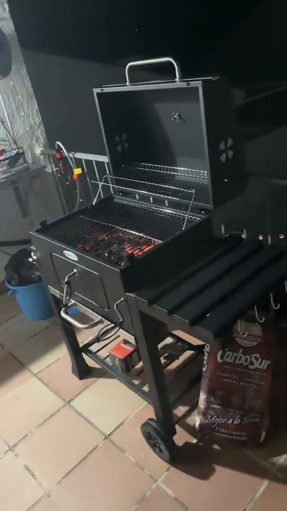 Parrilla de carbón con la tapa abierta y el carbón encendido en el brasero